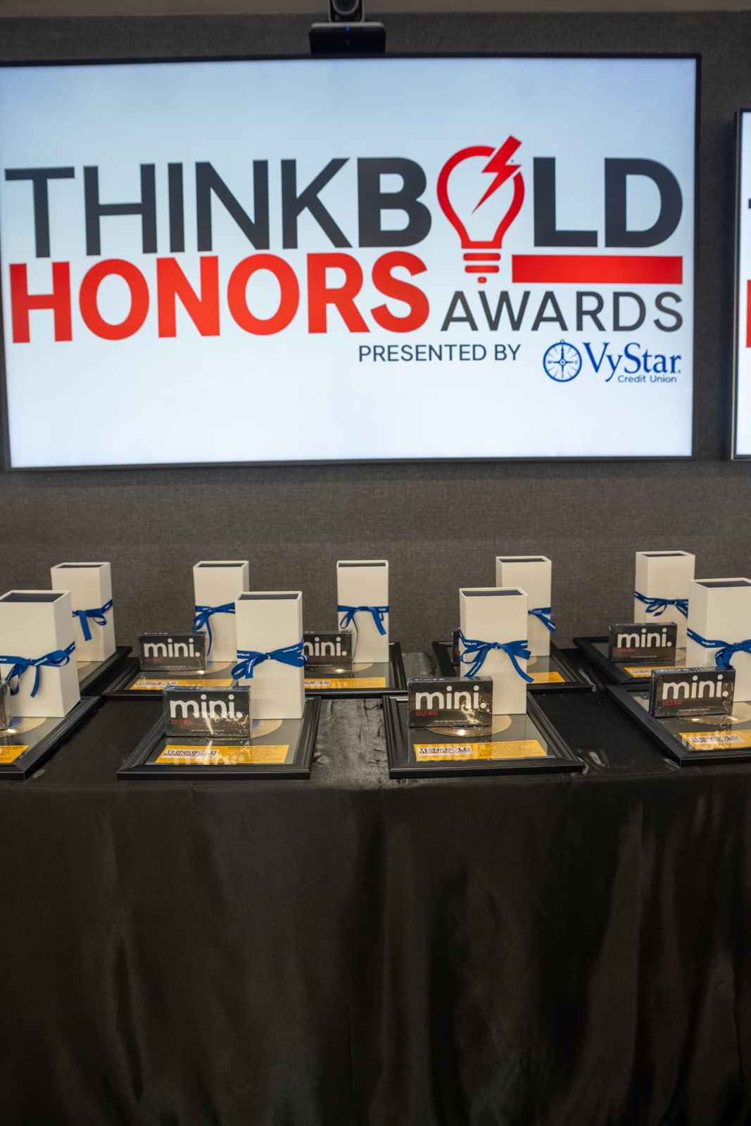 Award plaques and gifts lined up beneath the Think Bold Honors screen